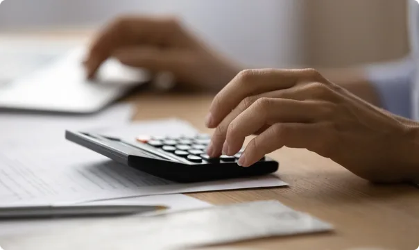 Manos calculando los costos de mudanza en una calculadora.