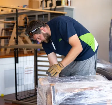 Mover unwrapping a protected cabinet after delivery