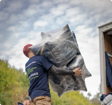 Operario de mudanzas sacando muebles envueltos en plástico de una casa.